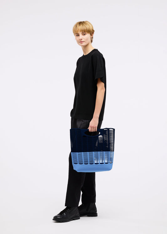 A model wears the GOOD GOODS ISSEY MIYAKE MOKKO BI COLOR bag.