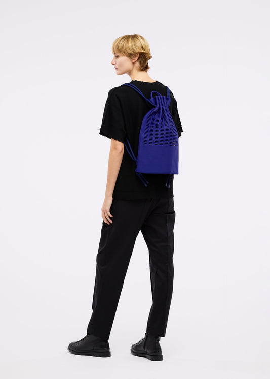 A model wears the GOOD GOODS ISSEY MIYAKE MOKKO KNAPSACK bag.