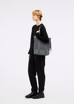 A model wears the GOOD GOODS ISSEY MIYAKE MOKKO MONO bag.