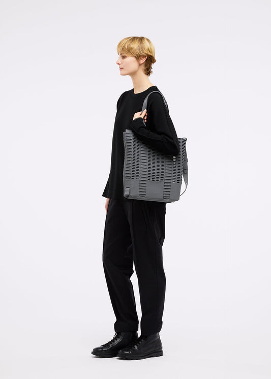 A model wears the GOOD GOODS ISSEY MIYAKE MOKKO MONO bag.