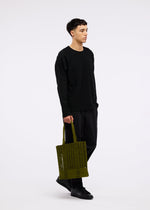 A model wears the GOOD GOODS ISSEY MIYAKE MOKKO MONO bag.