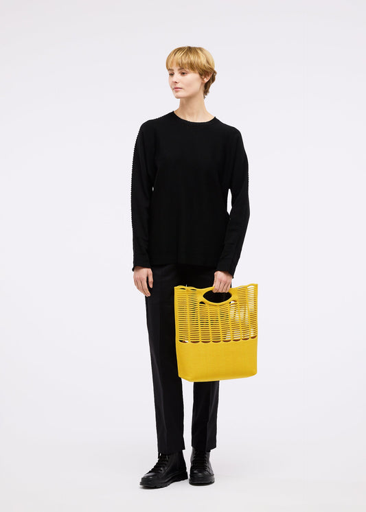 A model wears the GOOD GOODS ISSEY MIYAKE MOKKO TWILL bag.