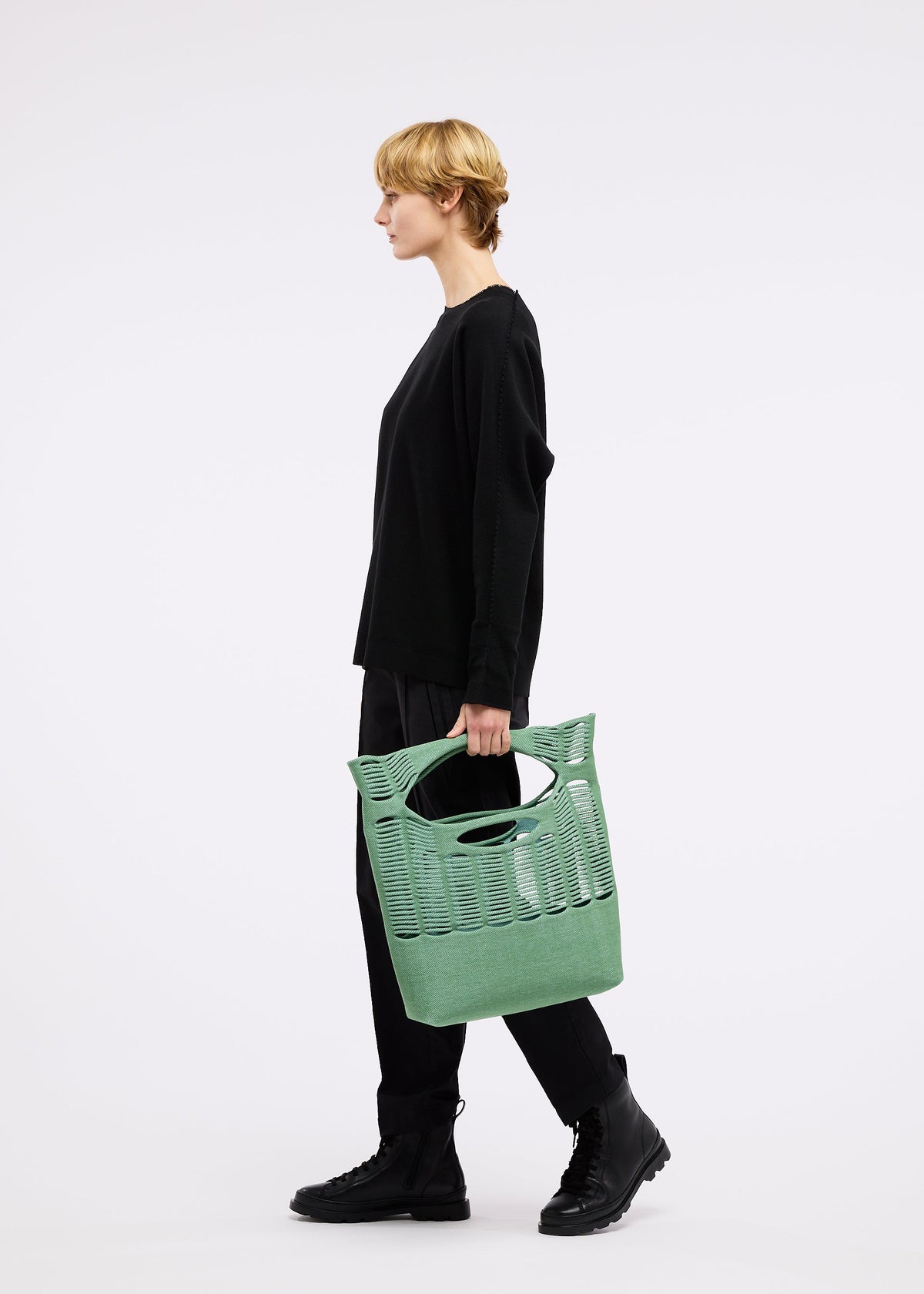 A model wears the GOOD GOODS ISSEY MIYAKE MOKKO TWILL bag.