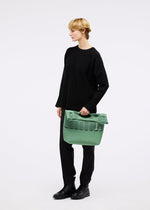 A model wears the GOOD GOODS ISSEY MIYAKE MOKKO TWILL bag.