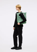 A model wears the GOOD GOODS ISSEY MIYAKE MOKKO TWILL bag.