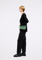 A model wears the GOOD GOODS ISSEY MIYAKE MOKKO TWILL bag.