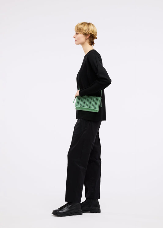 A model wears the GOOD GOODS ISSEY MIYAKE MOKKO TWILL bag.