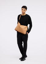 A model wears the GOOD GOODS ISSEY MIYAKE ROLL bag.