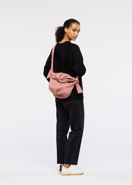 A model wears the GOOD GOODS ISSEY MIYAKE FUWA FUWA bags.