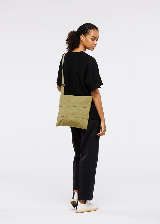 A model wears the GOOD GOODS ISSEY MIYAKE GRID bag.