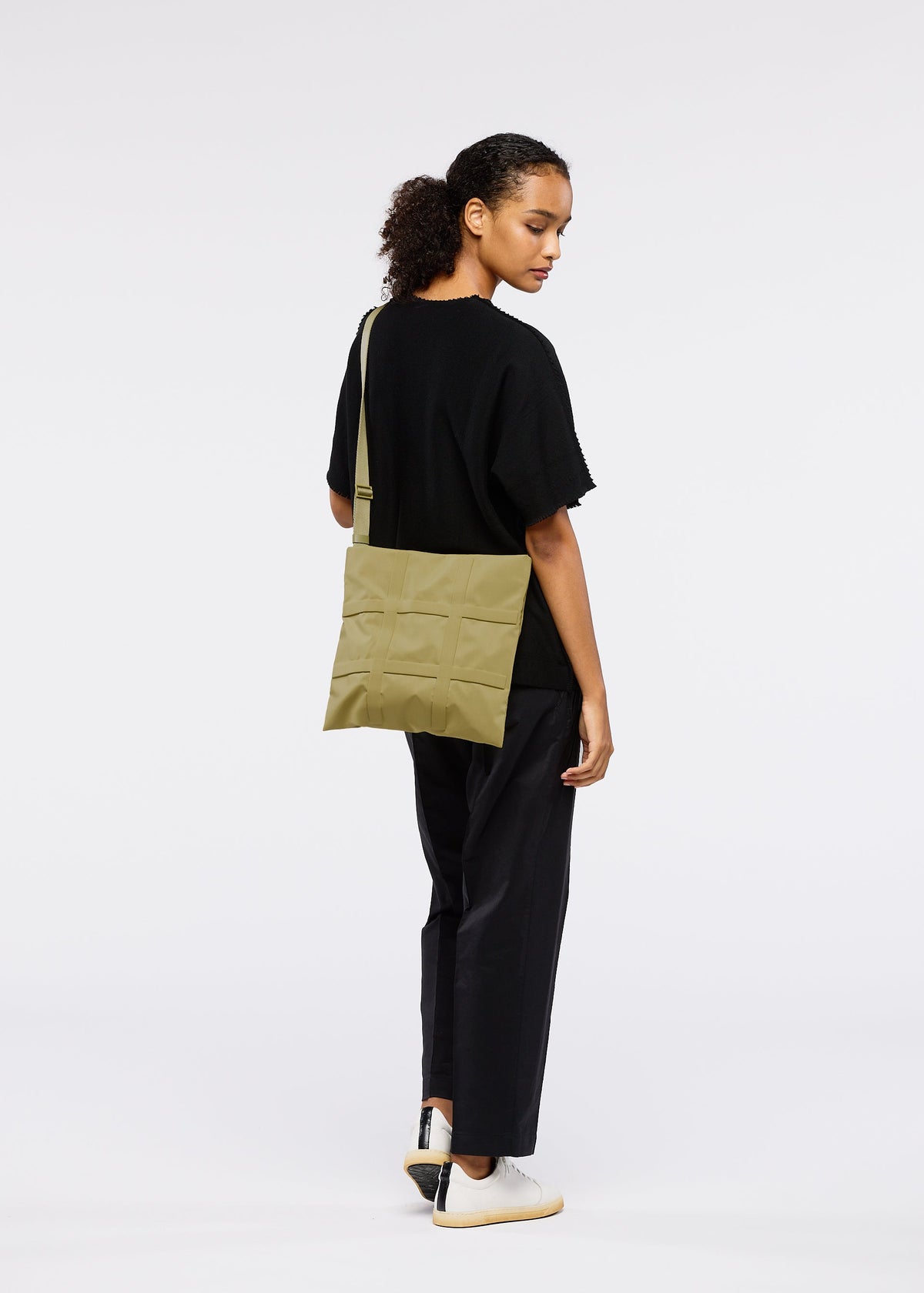 A model wears the GOOD GOODS ISSEY MIYAKE GRID bag.