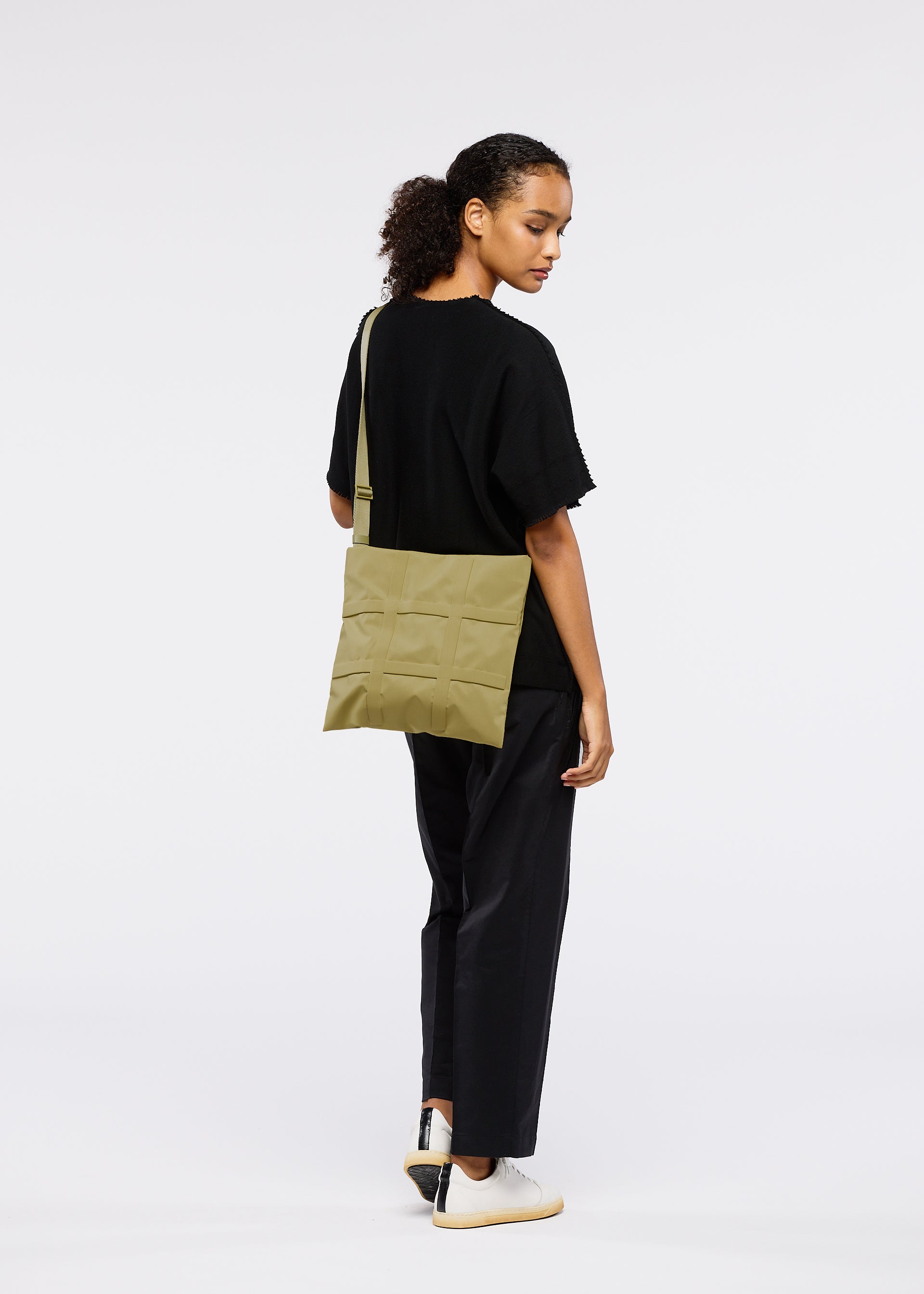 A model wears the GOOD GOODS ISSEY MIYAKE GRID bag.