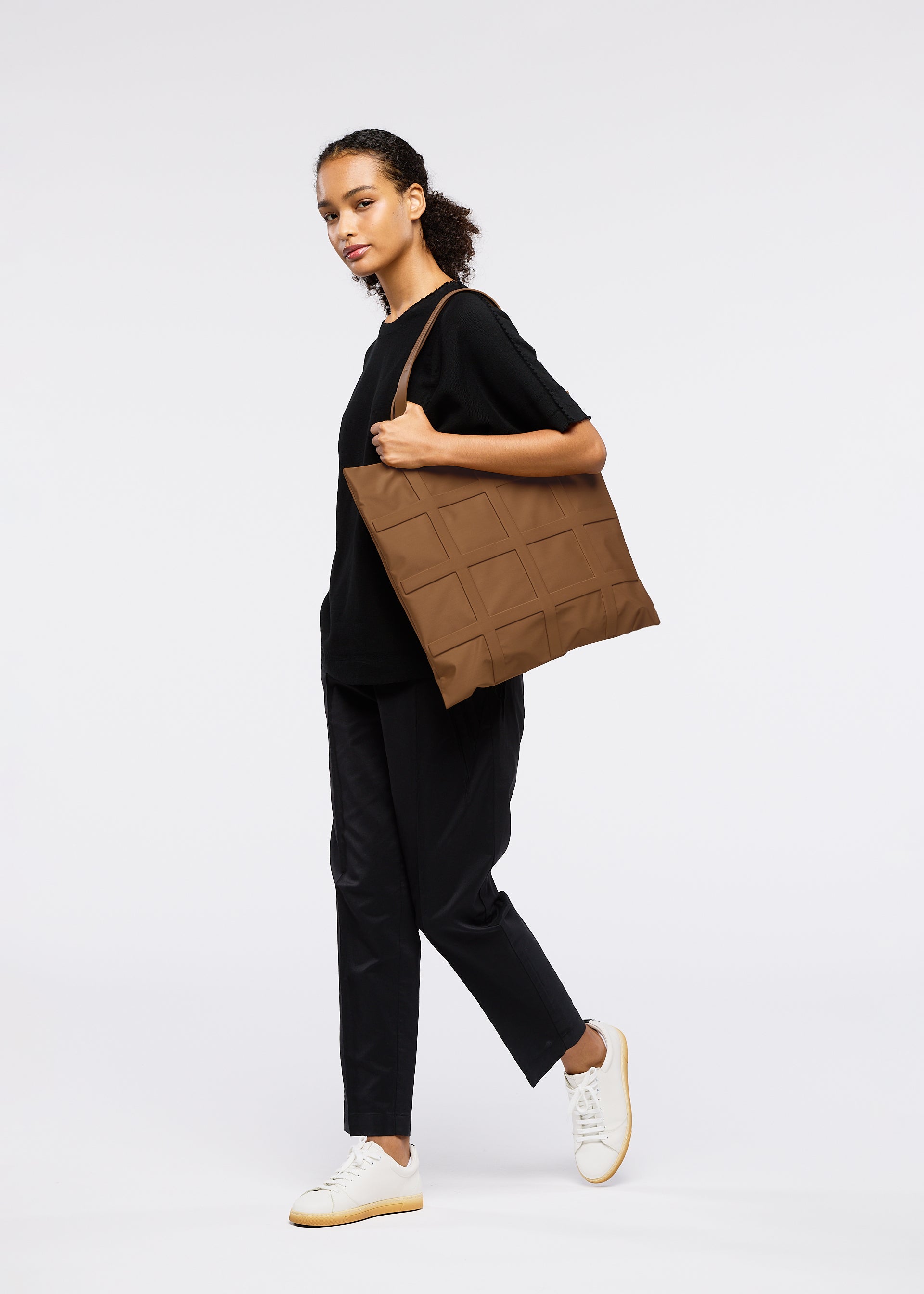A model wears the GOOD GOODS ISSEY MIYAKE GRID bag.