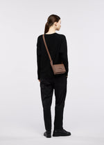 A model wears the GOOD GOODS ISSEY MIYAKE BOX box-handbag-dark-brown.