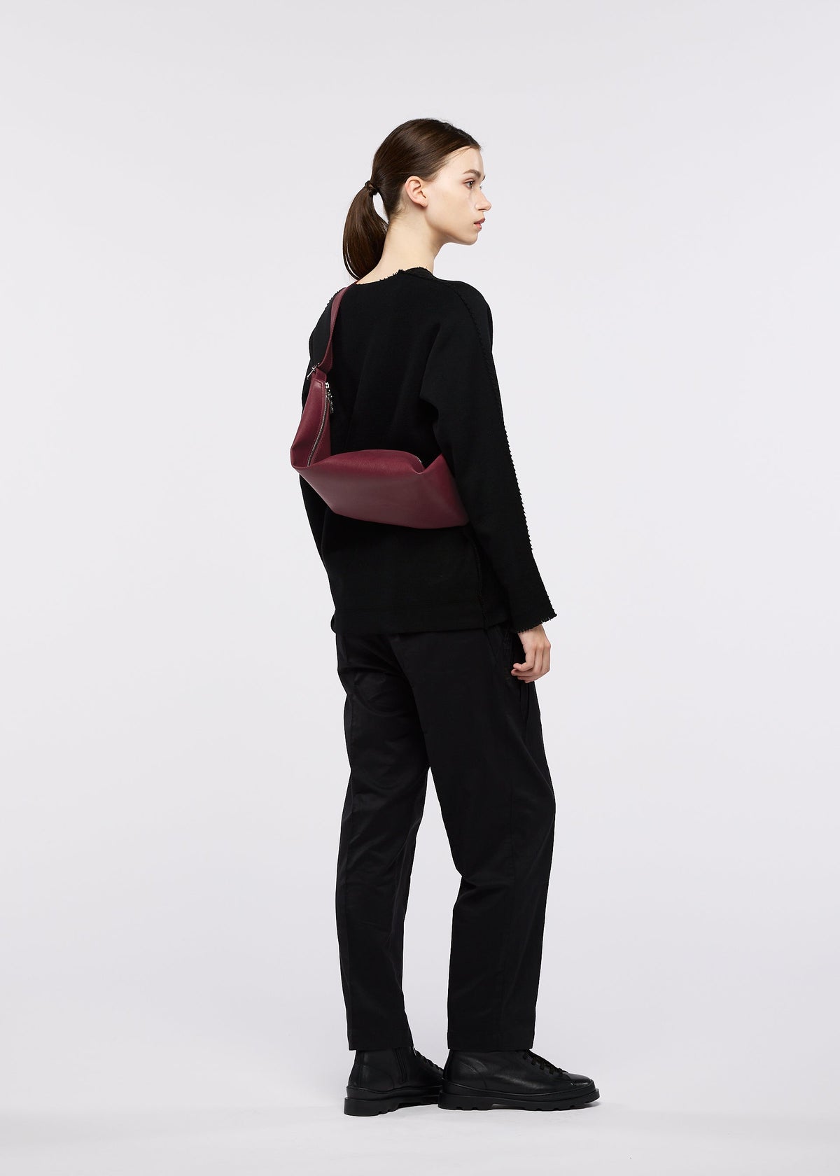 A model wears the GOOD GOODS ISSEY MIYAKE LEAF leaf-hand-bag-black.