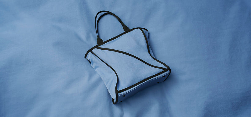 Centre: WAKU Bag in Light Blue against light blue fabric background.