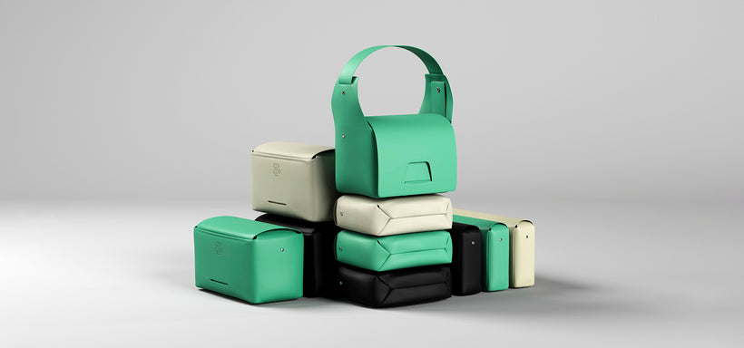 Centre: BOX Bags in Black, Cream and Emerald stacked on top of each other, against light grey background.