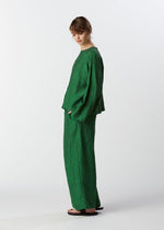 A model wears the HAAT GLOSSY LINEN trousers.