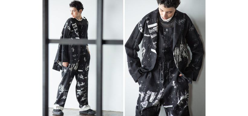 Left: Model wearing the KOKUYU Jacket and Jumpsuit in Black, standing behind a metal frame against a grey background. Right: Model wearing the KOKUYU Jacket and Jumpsuit in Black, standing against a grey background.