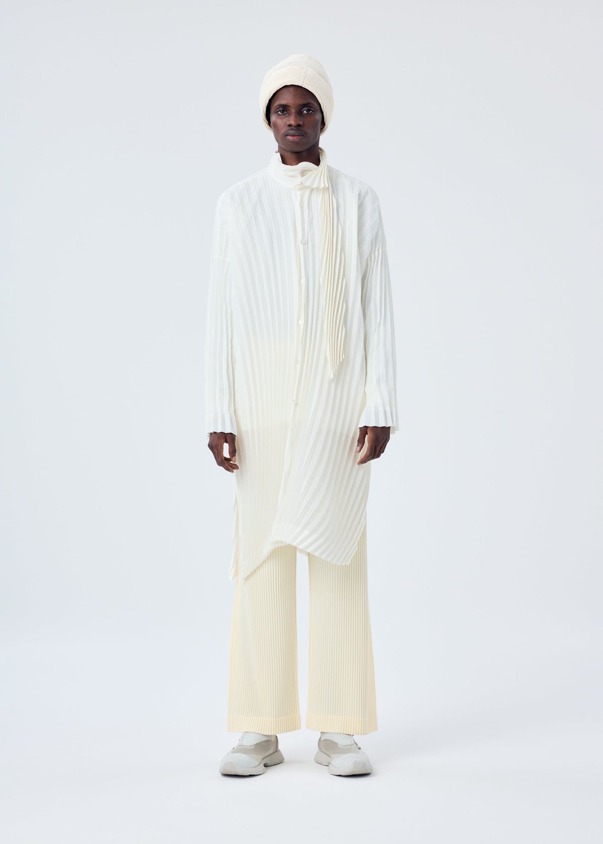 A model wears the HOMME PLISSÉ ISSEY MIYAKE BEANIE SCARF hat.