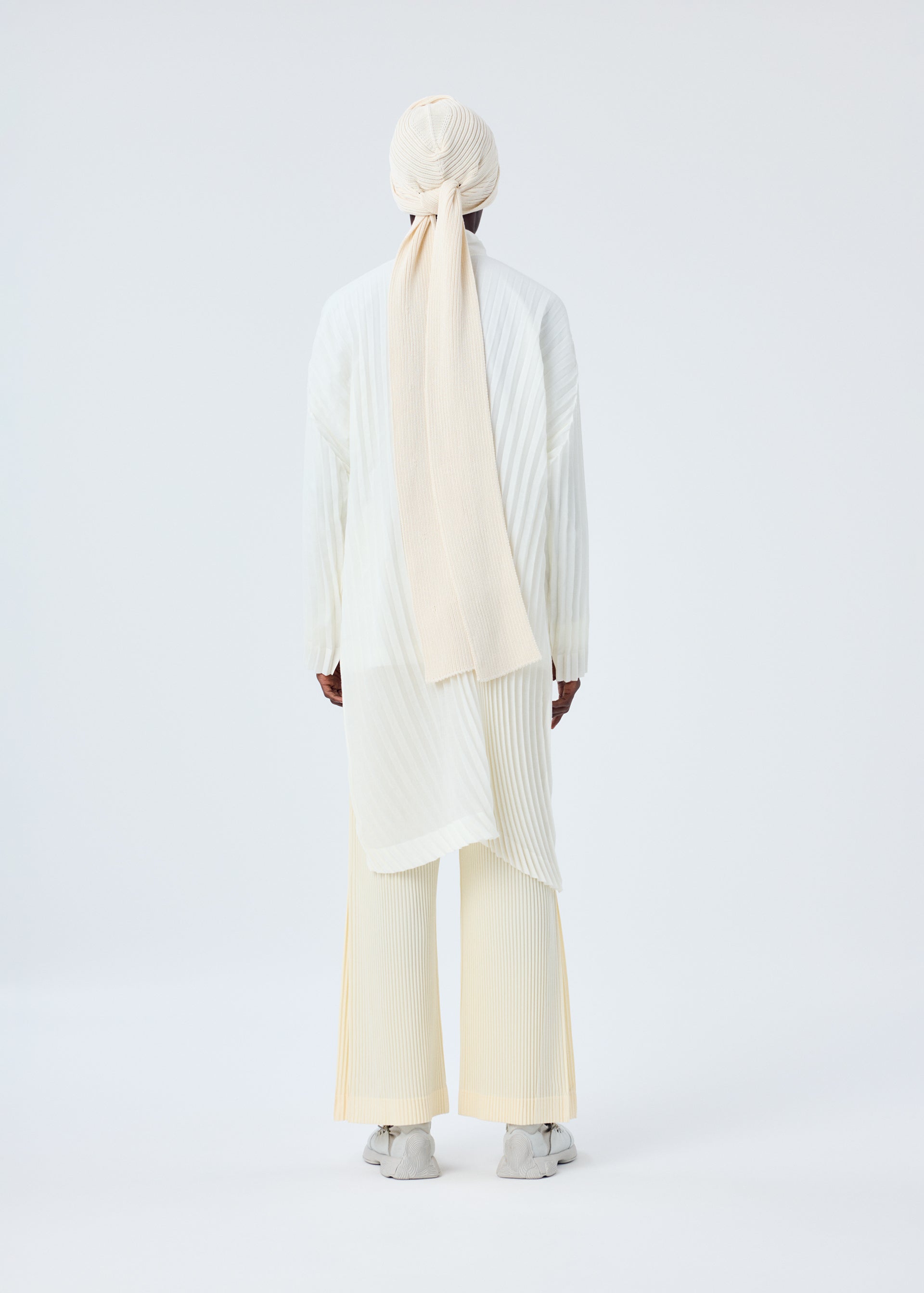 A model wears the HOMME PLISSÉ ISSEY MIYAKE BEANIE SCARF hat.