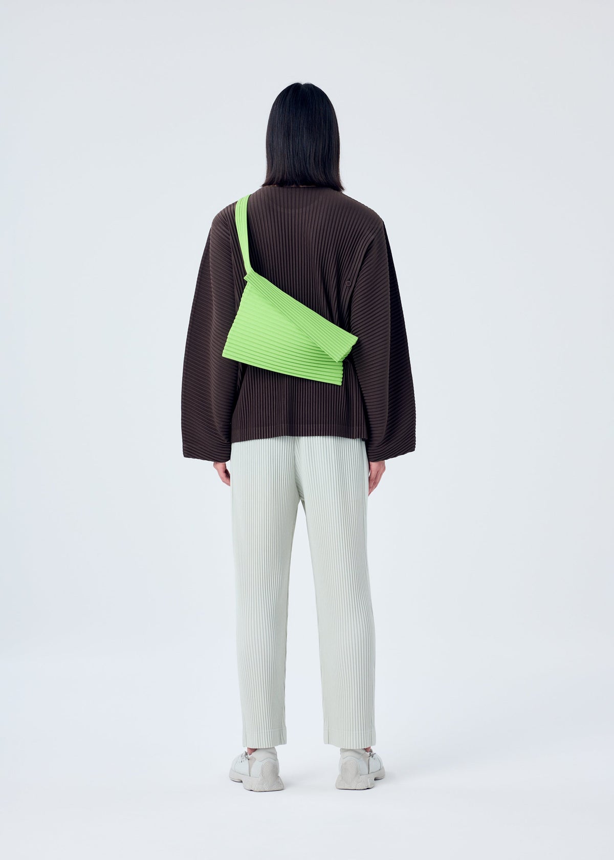 A model wears the HOMME PLISSÉ ISSEY MIYAKE OVERLAP bag.