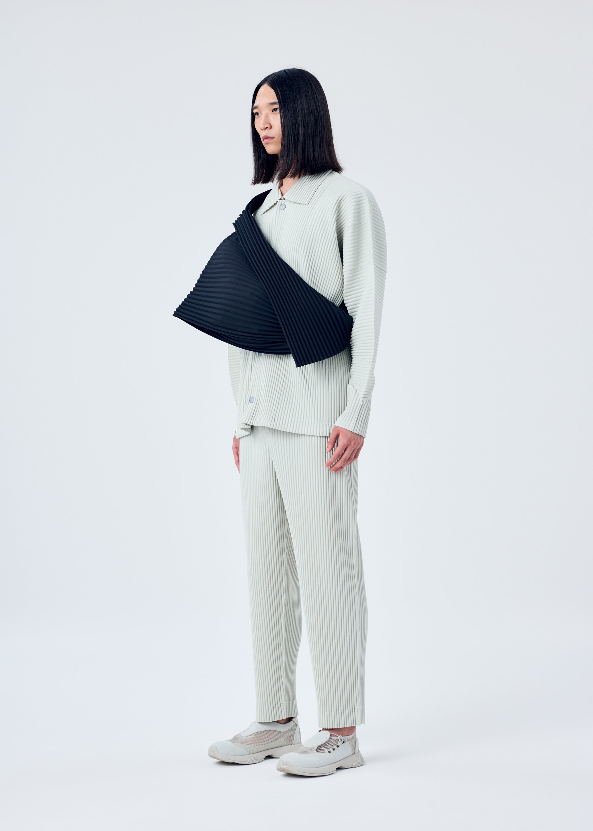 A model wears the HOMME PLISSÉ ISSEY MIYAKE OVERLAP bag.