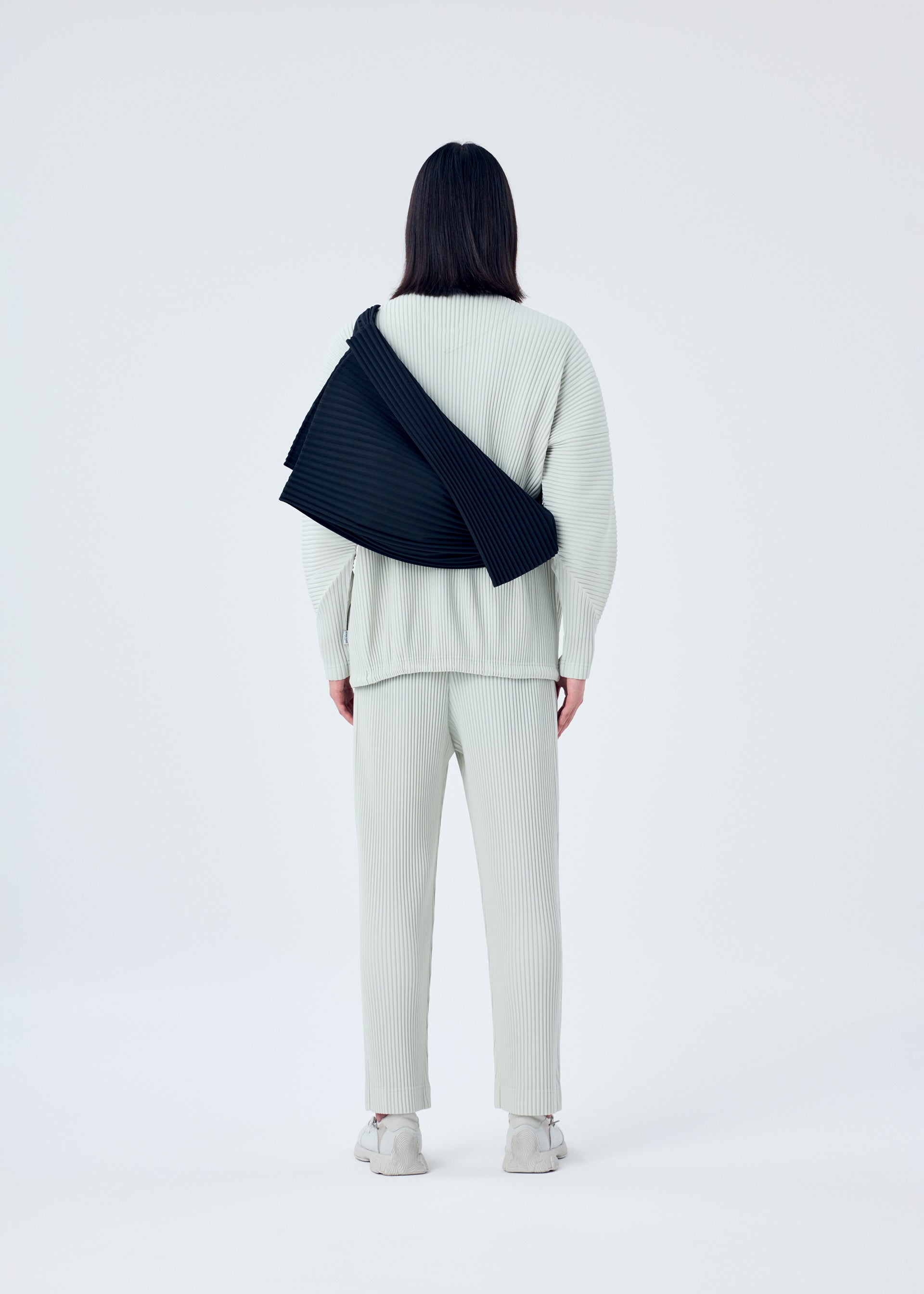 A model wears the HOMME PLISSÉ ISSEY MIYAKE OVERLAP bag.