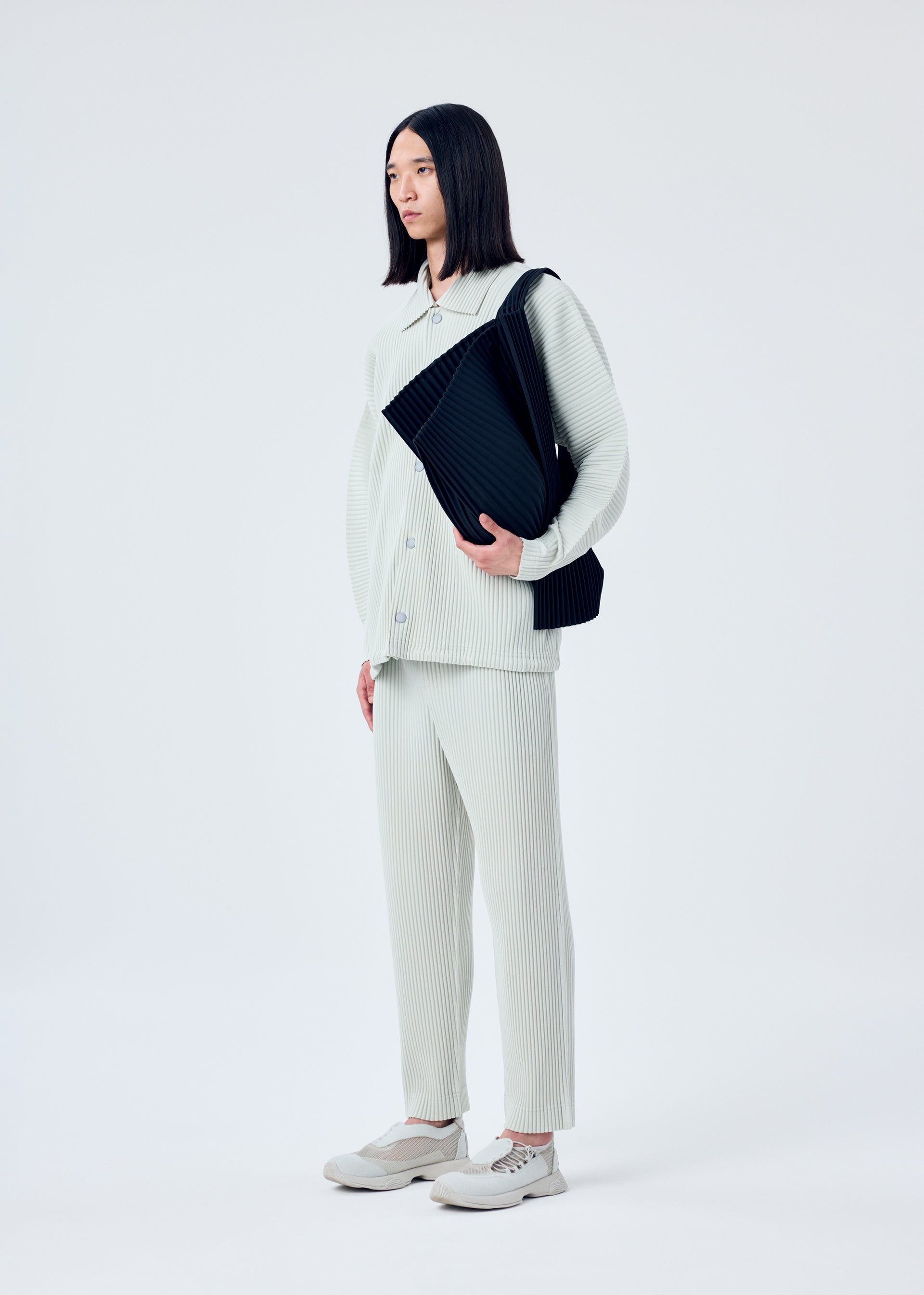A model wears the HOMME PLISSÉ ISSEY MIYAKE OVERLAP bag.