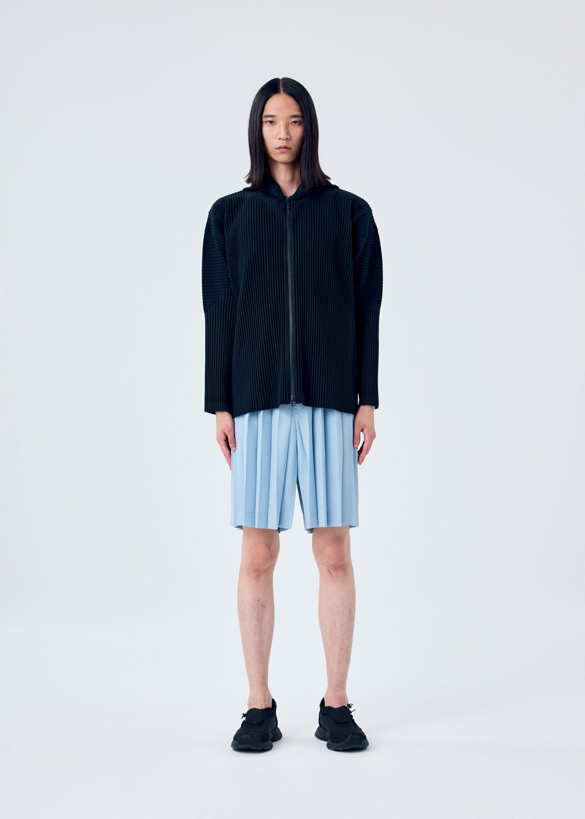 A model wears the HOMME PLISSÉ ISSEY MIYAKE EDGE ENSEMBLE trousers.
