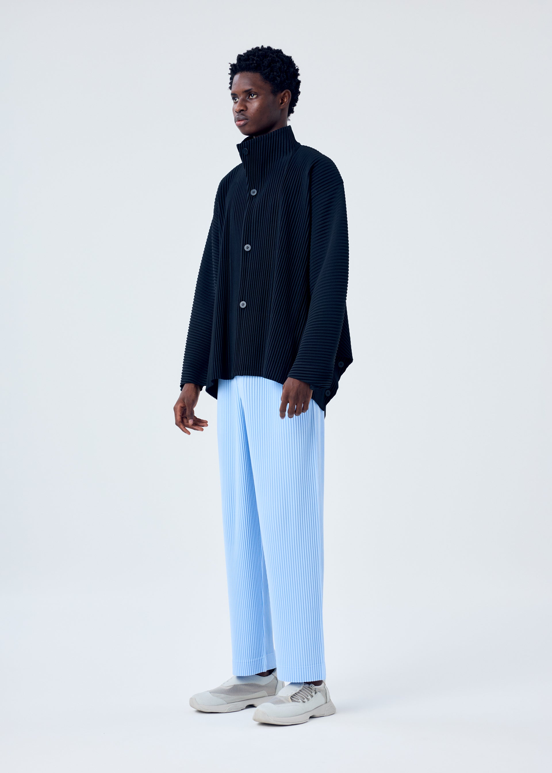 A model wears the HOMME PLISSÉ ISSEY MIYAKE MC JANUARY trousers.