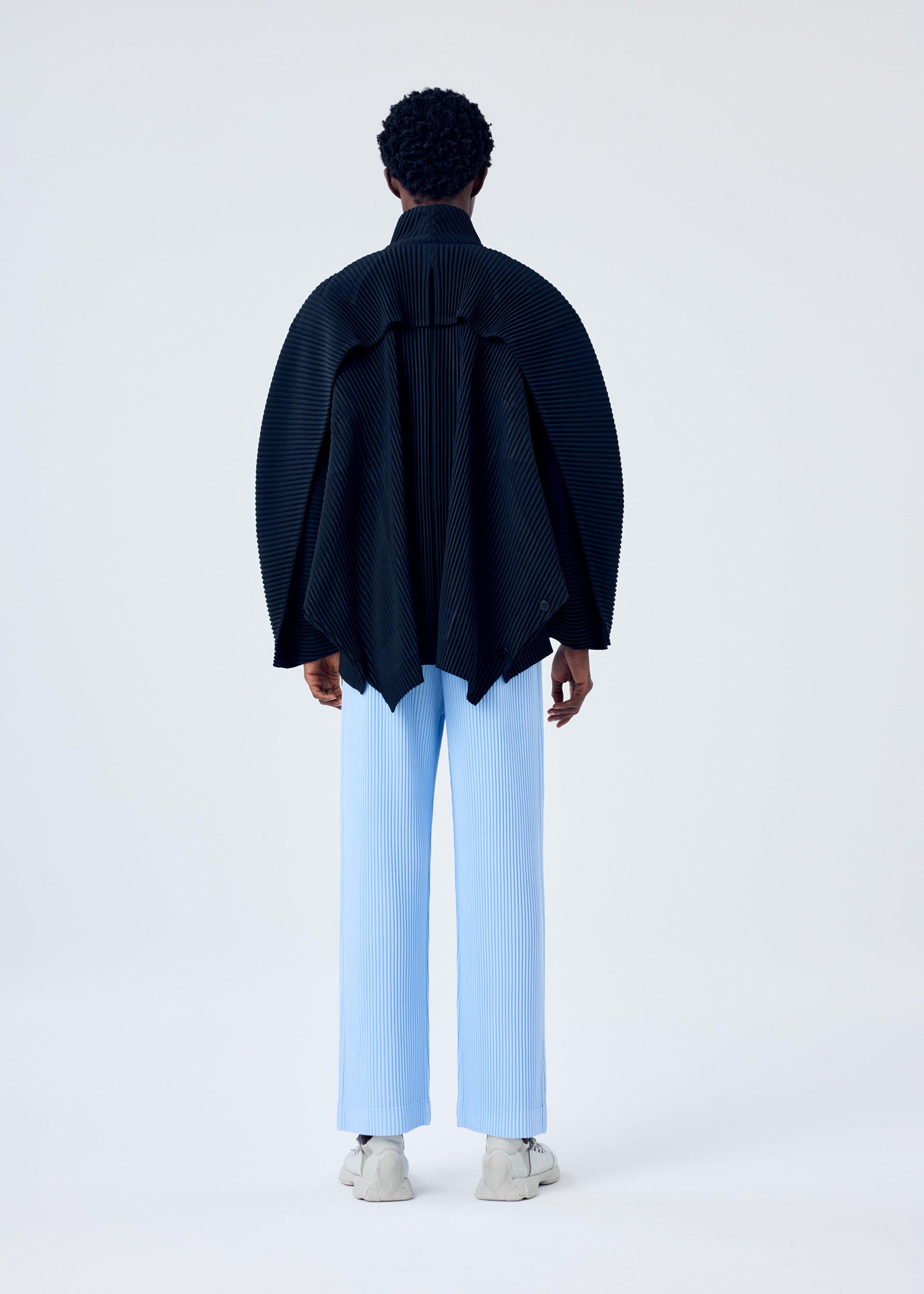 A model wears the HOMME PLISSÉ ISSEY MIYAKE MC JANUARY trousers.