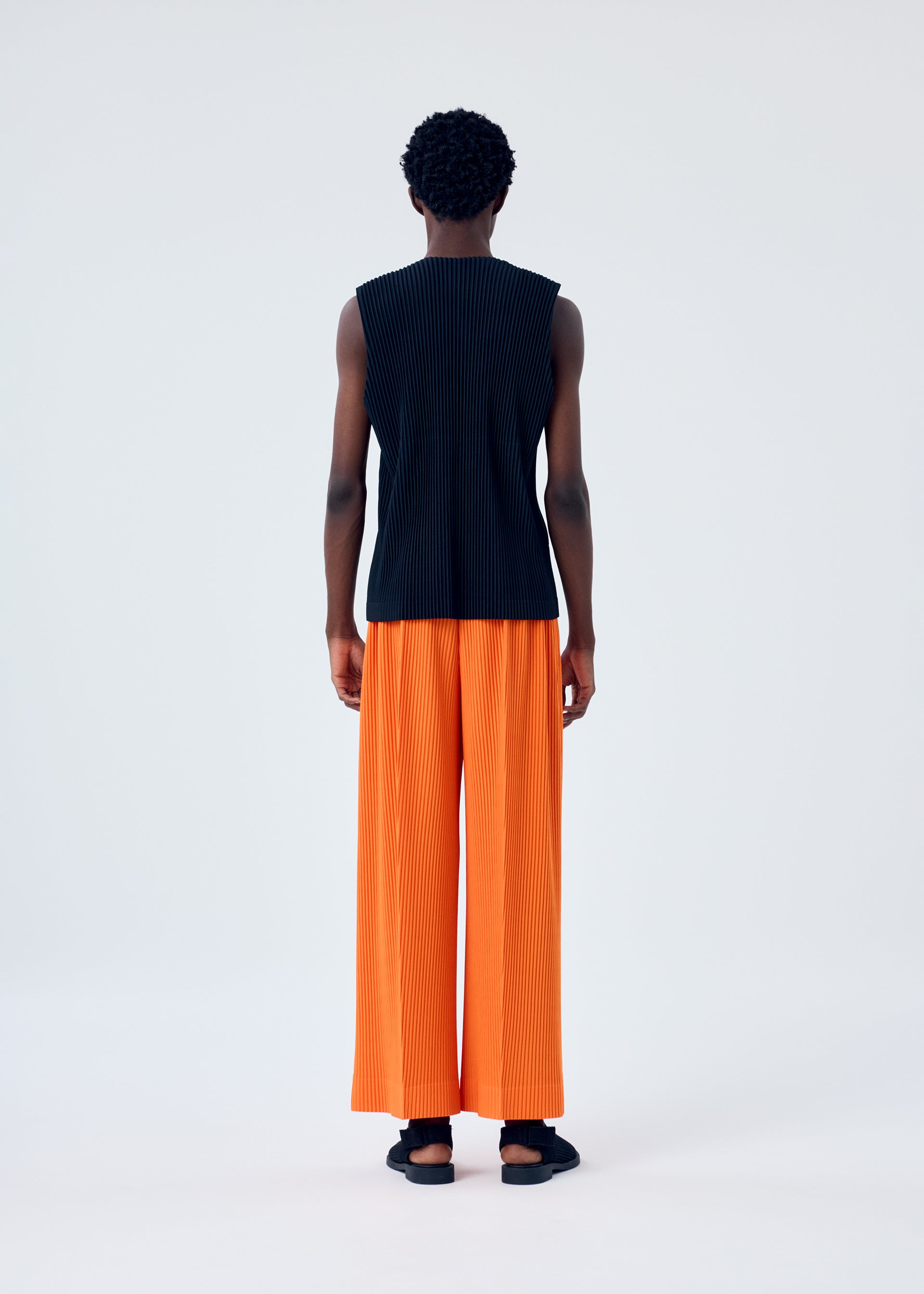 A model wears the HOMME PLISSÉ ISSEY MIYAKE MC FEBRUARY trousers.