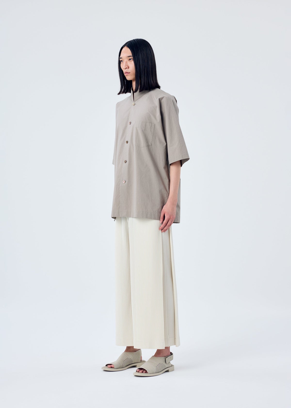 A model wears the HOMME PLISSÉ ISSEY MIYAKE MC MAY trousers.