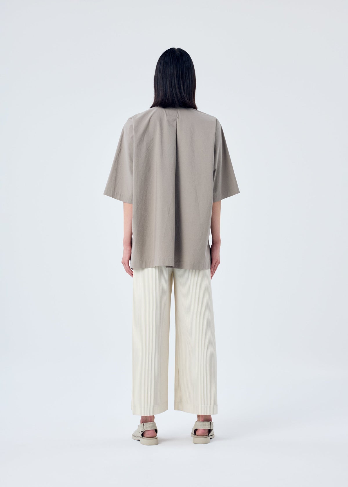 A model wears the HOMME PLISSÉ ISSEY MIYAKE MC MAY trousers.