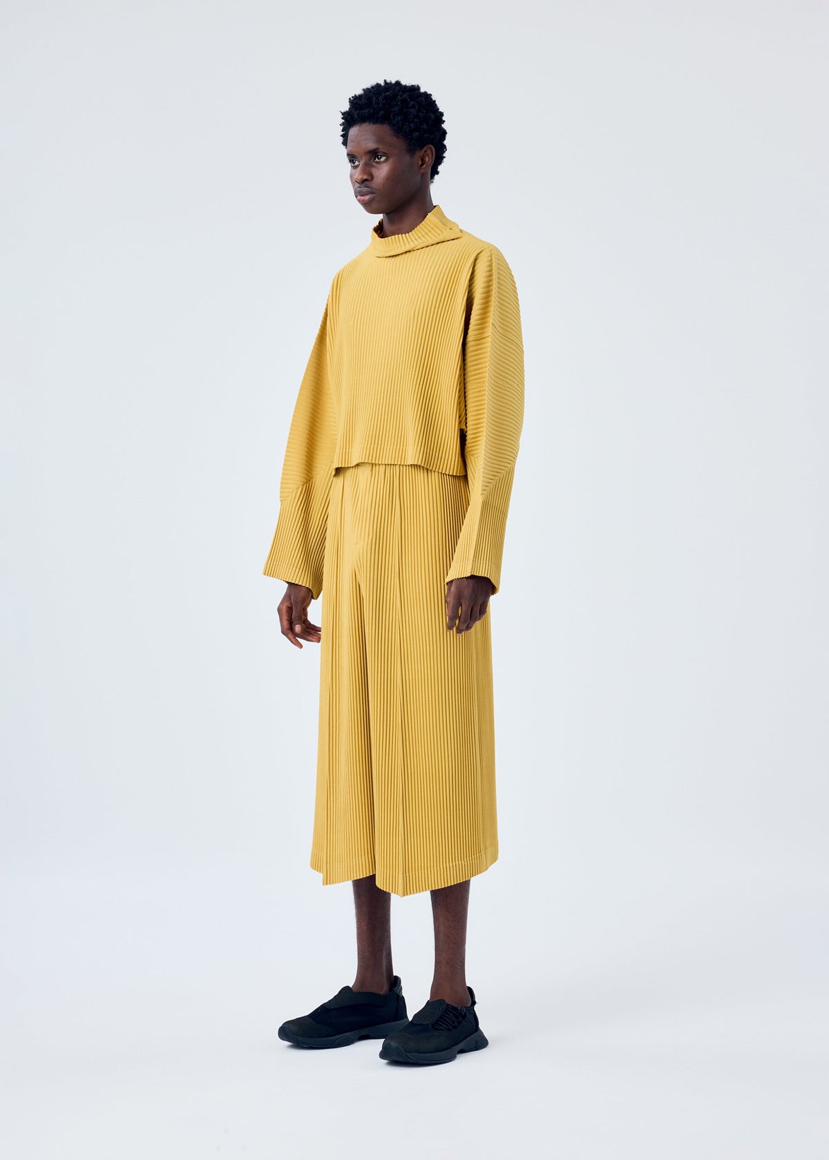 A model wears the HOMME PLISSÉ ISSEY MIYAKE MC JUNE trousers.