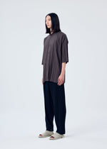 A model wears the HOMME PLISSÉ ISSEY MIYAKE PLEATS BOTTOMS 1 trousers.