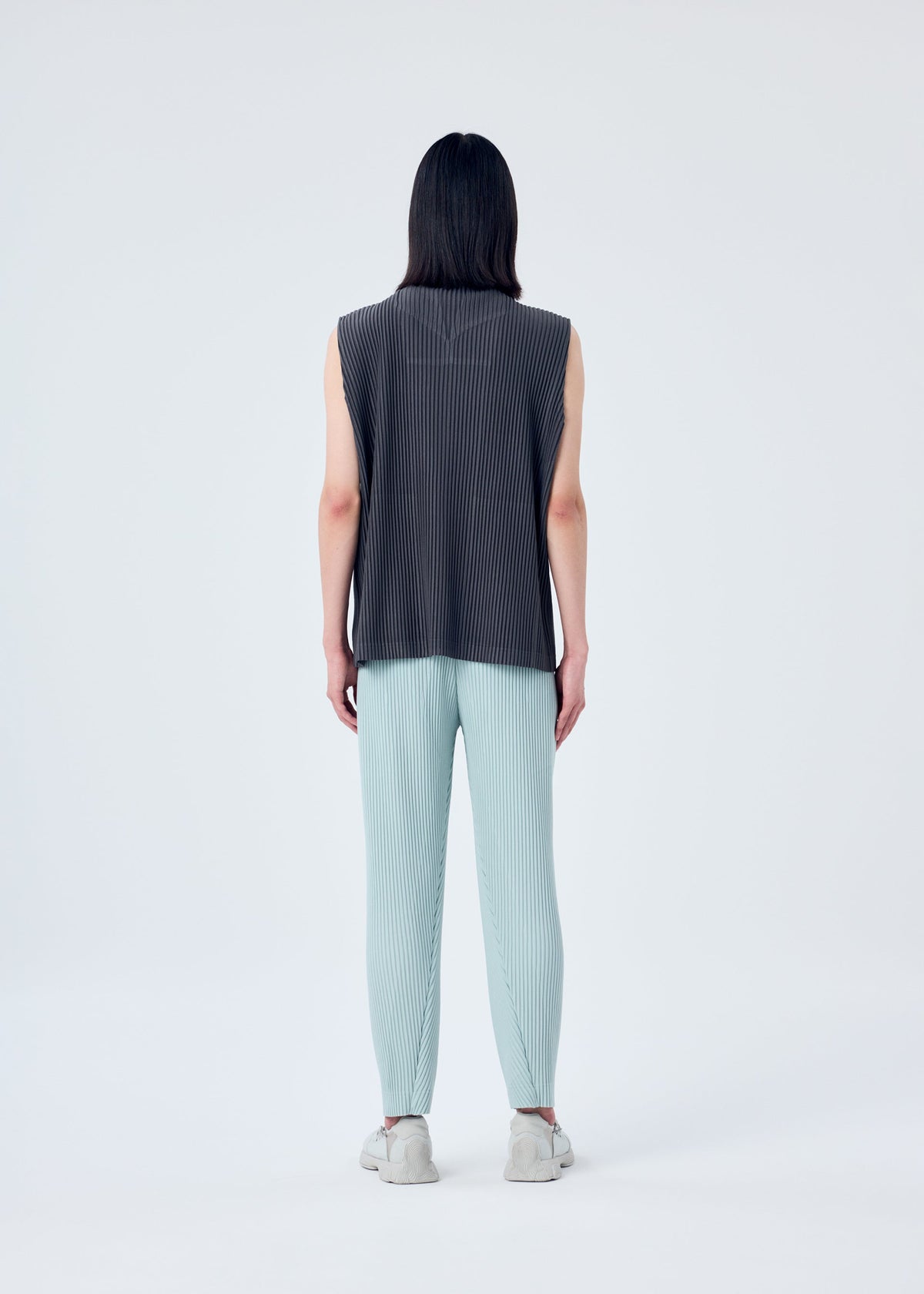 A model wears the HOMME PLISSÉ ISSEY MIYAKE PLEATS BOTTOMS 2 trousers.