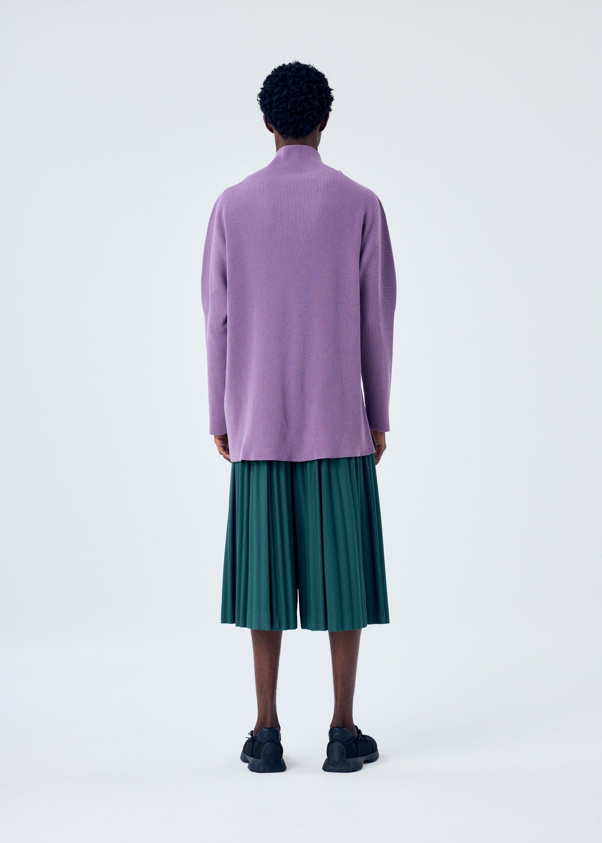 A model wears the HOMME PLISSÉ ISSEY MIYAKE TAILORED PLEATS 1 trousers.