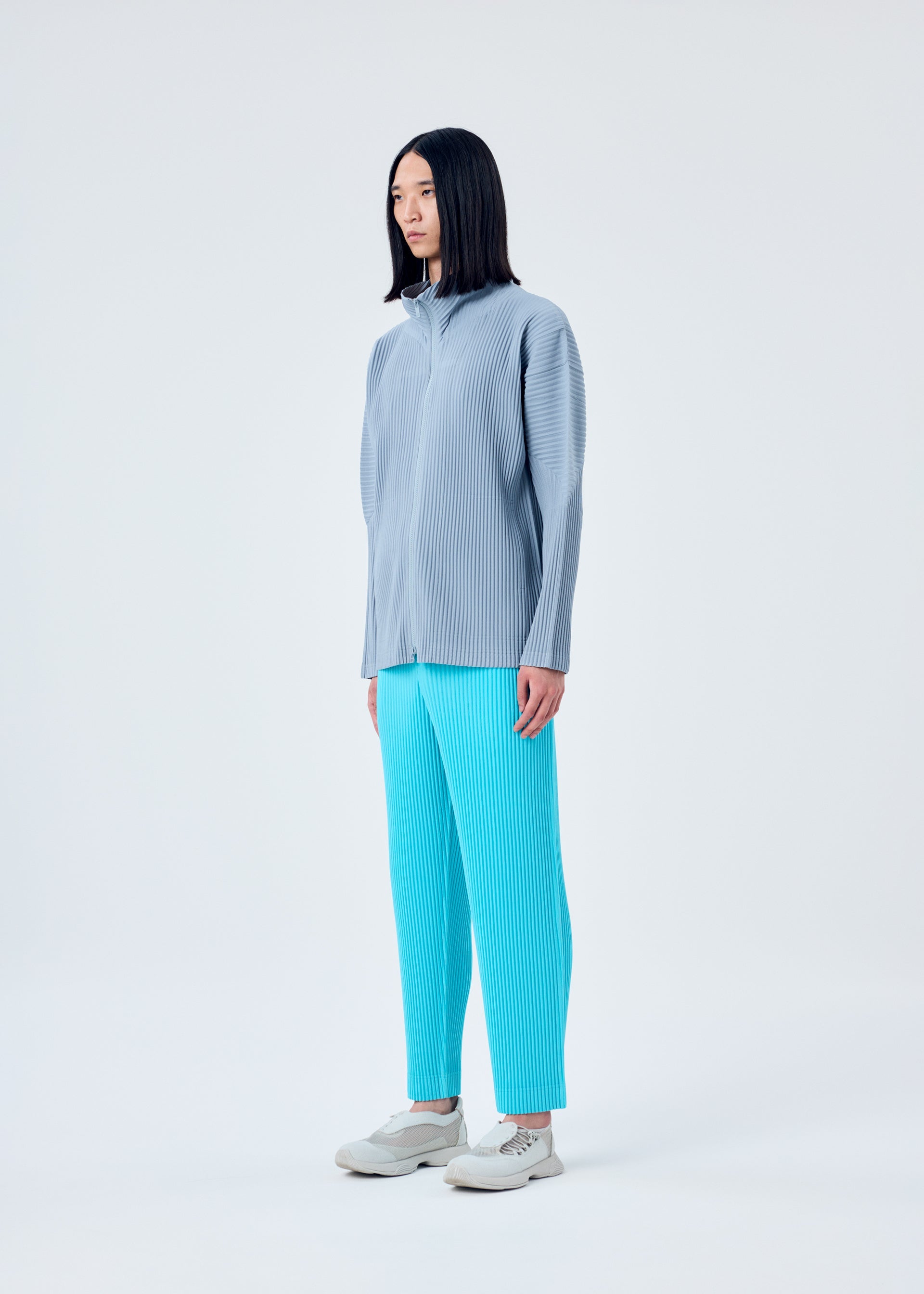 A model wears the HOMME PLISSÉ ISSEY MIYAKE COLOR PLEATS trousers.