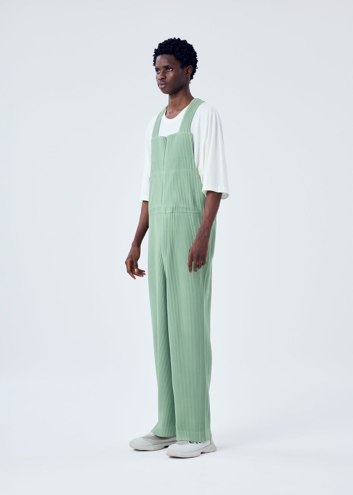 A model wears the HOMME PLISSÉ ISSEY MIYAKE PLEATS BOTTOMS 1 jumpsuit.