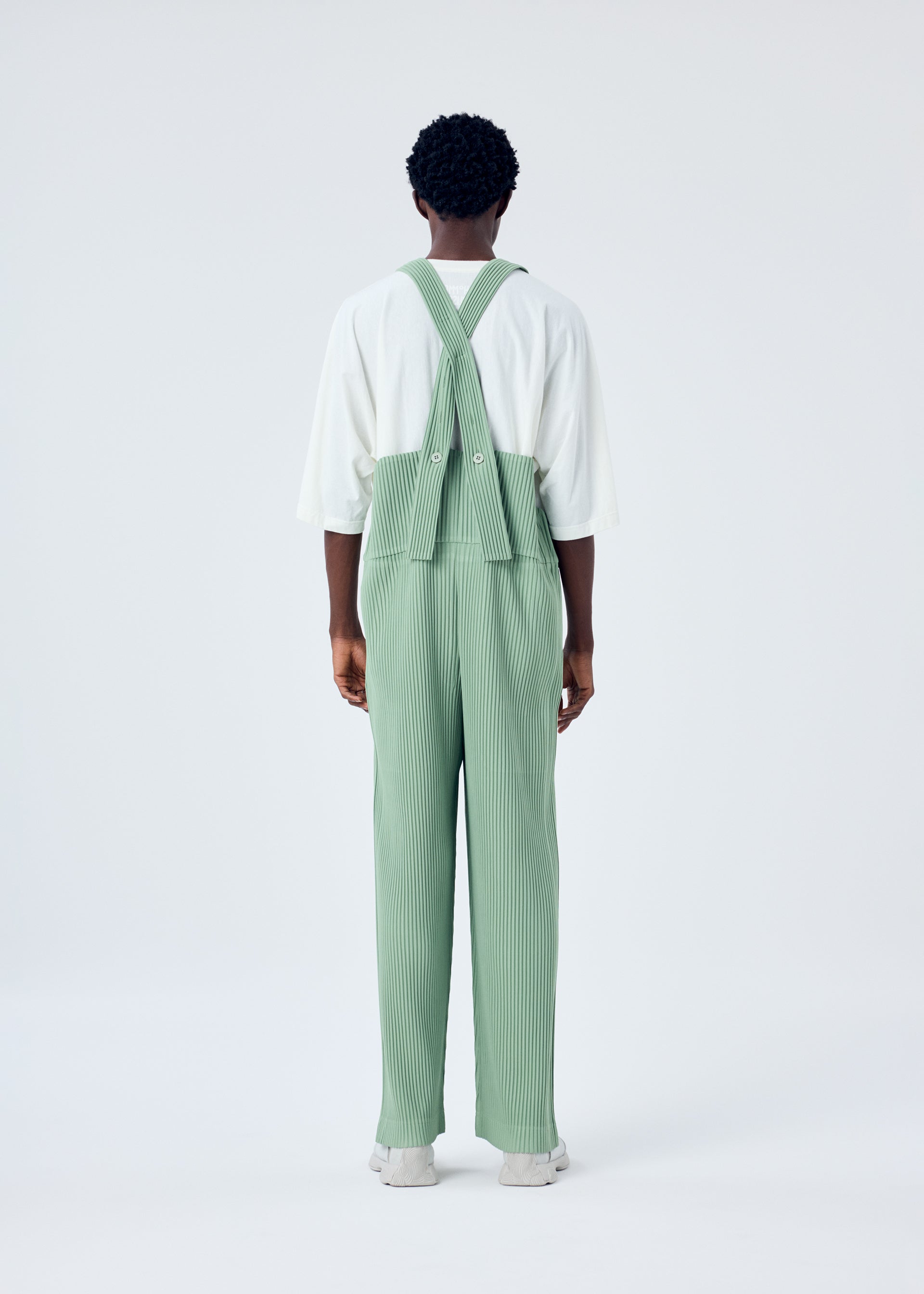 A model wears the HOMME PLISSÉ ISSEY MIYAKE PLEATS BOTTOMS 1 jumpsuit.