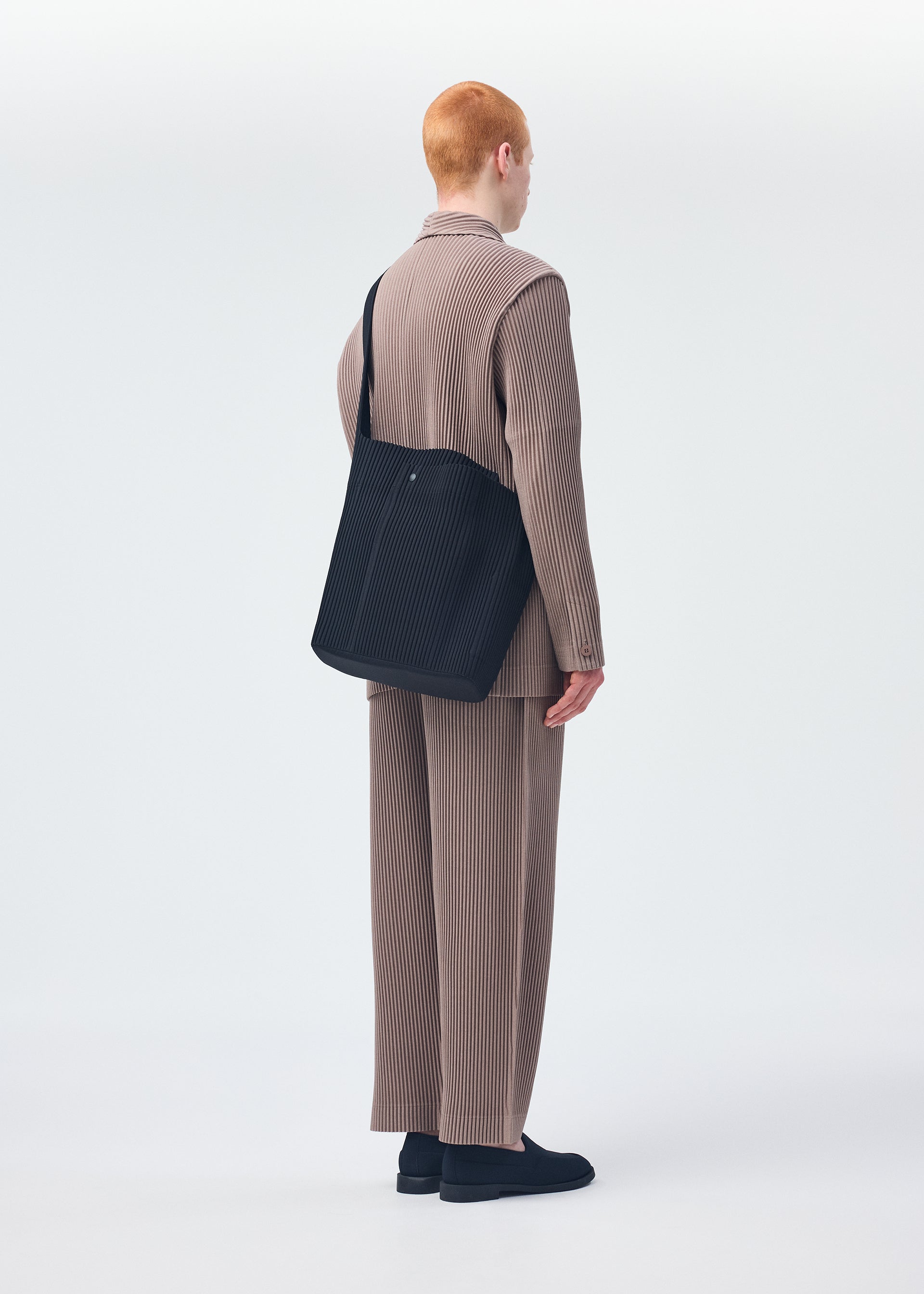 A model wears the HOMME PLISSÉ ISSEY MIYAKE UTILITY bag.