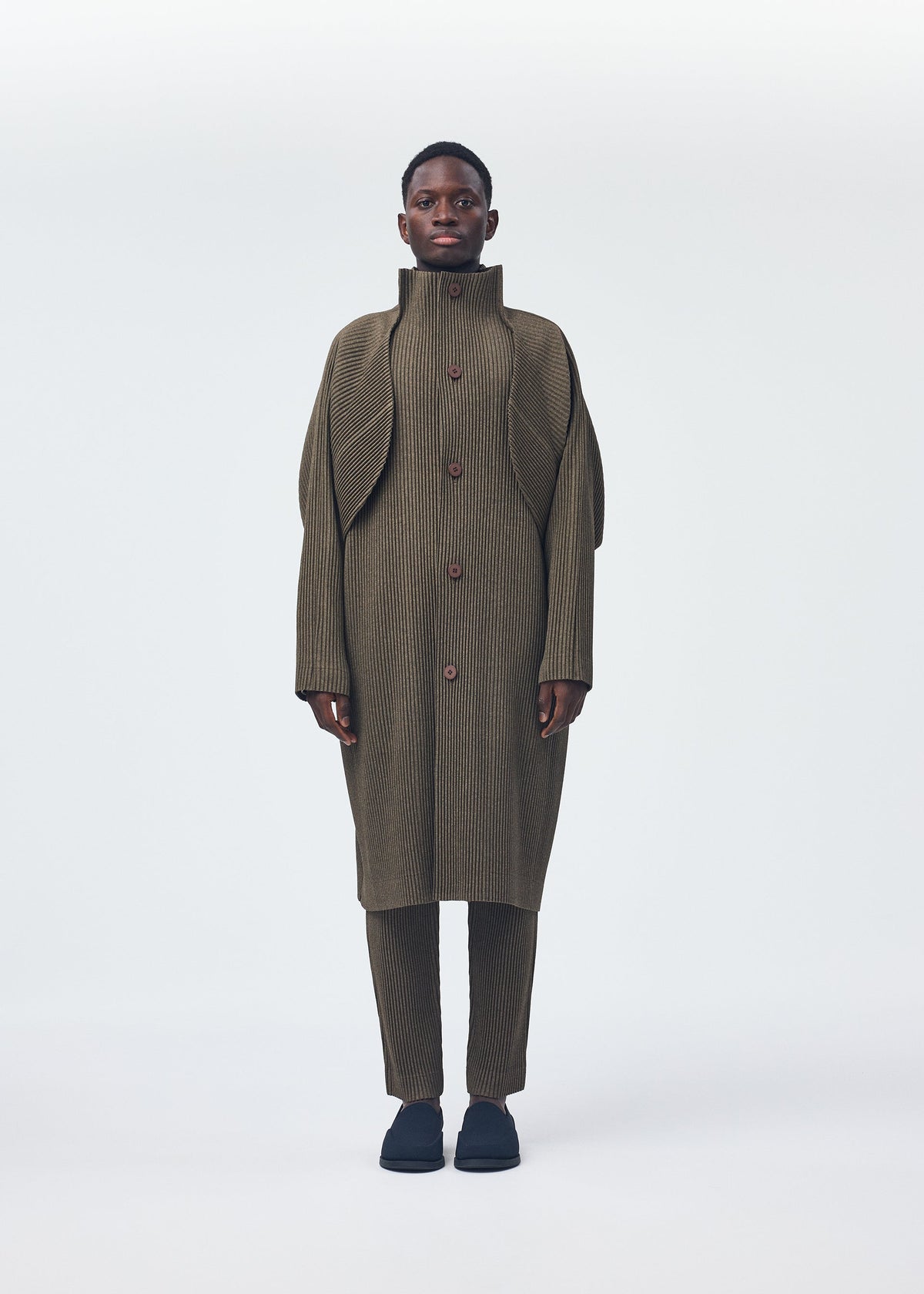 A model wears the HOMME PLISSÉ ISSEY MIYAKE WOOL LIKE LIGHT coat.