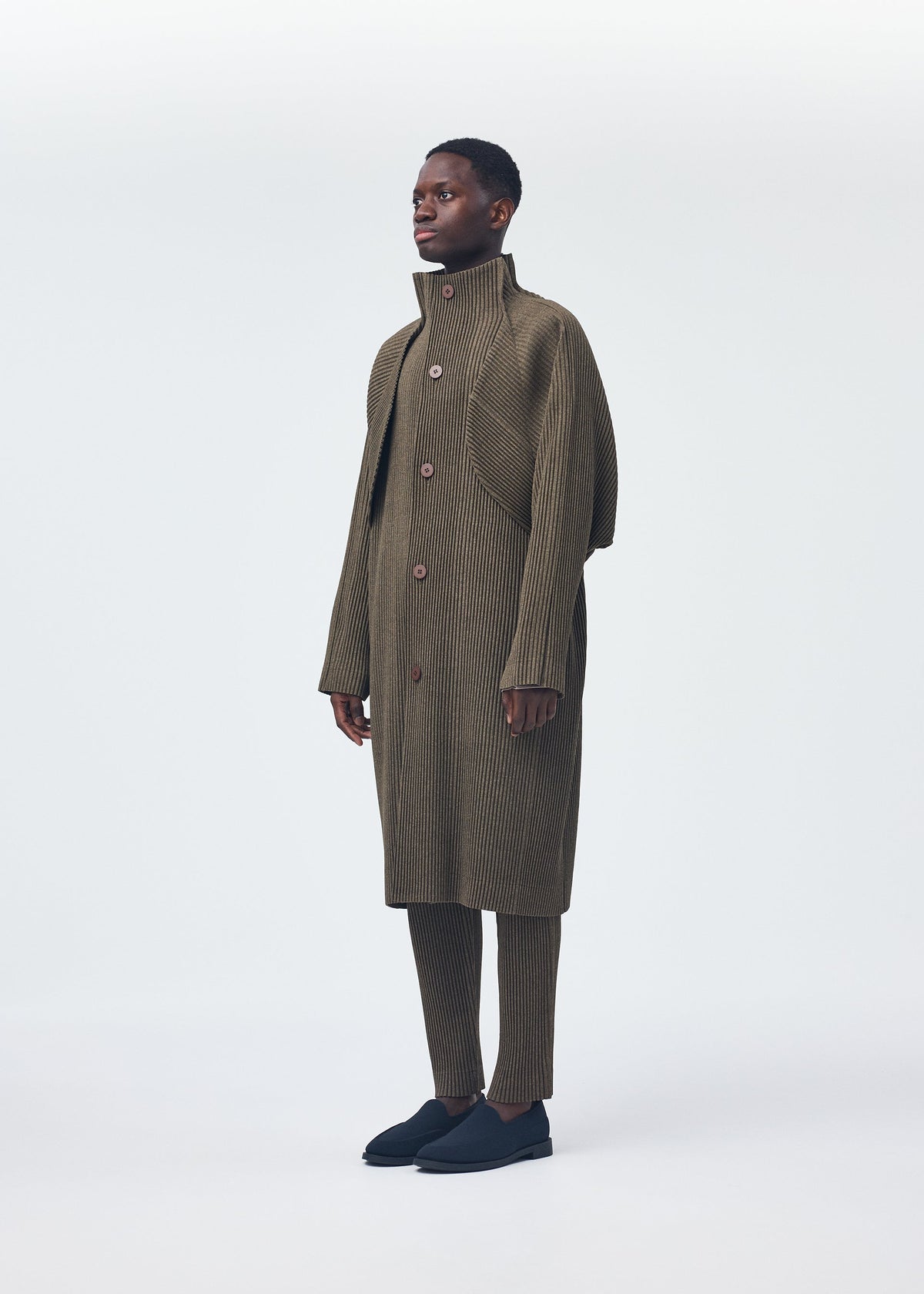 A model wears the HOMME PLISSÉ ISSEY MIYAKE WOOL LIKE LIGHT coat.