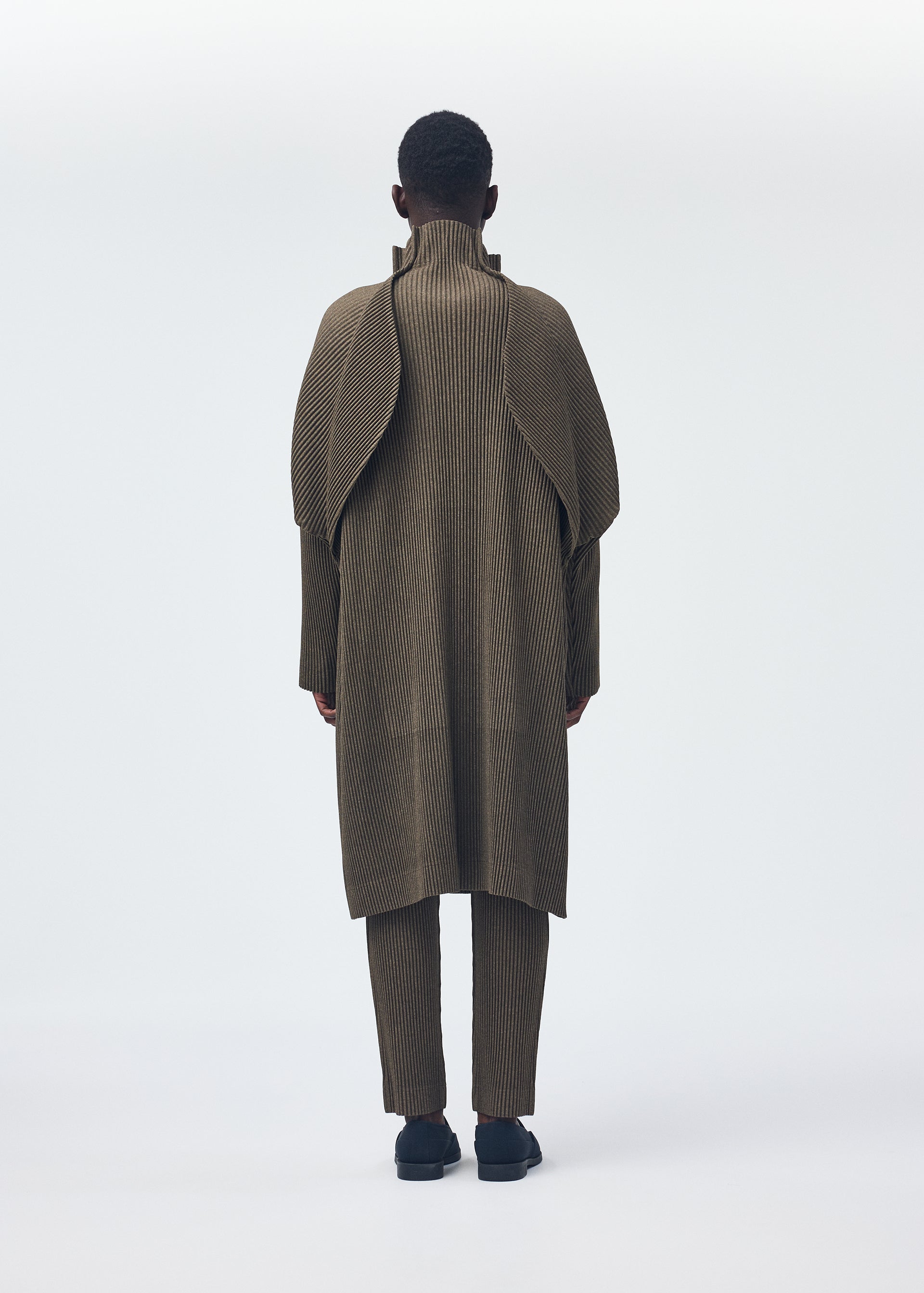 A model wears the HOMME PLISSÉ ISSEY MIYAKE WOOL LIKE LIGHT coat.