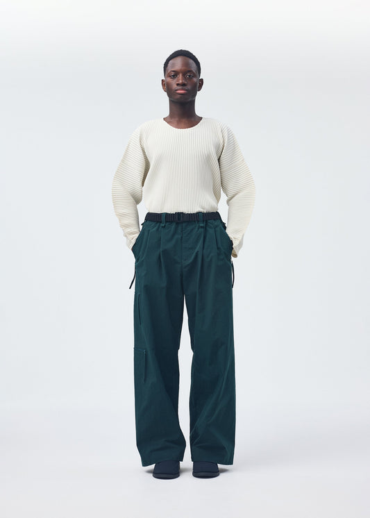 A model wears the HOMME PLISSÉ ISSEY MIYAKE QUARRY PANTS trousers.