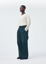A model wears the HOMME PLISSÉ ISSEY MIYAKE QUARRY PANTS trousers.