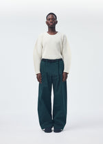 A model wears the HOMME PLISSÉ ISSEY MIYAKE QUARRY PANTS trousers.