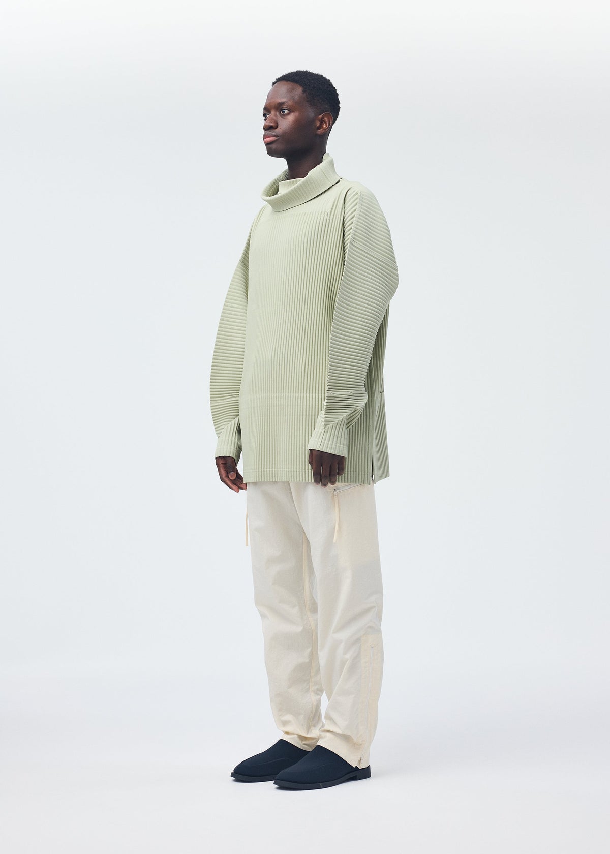 A model wears the HOMME PLISSÉ ISSEY MIYAKE QUARRY PANTS trousers.